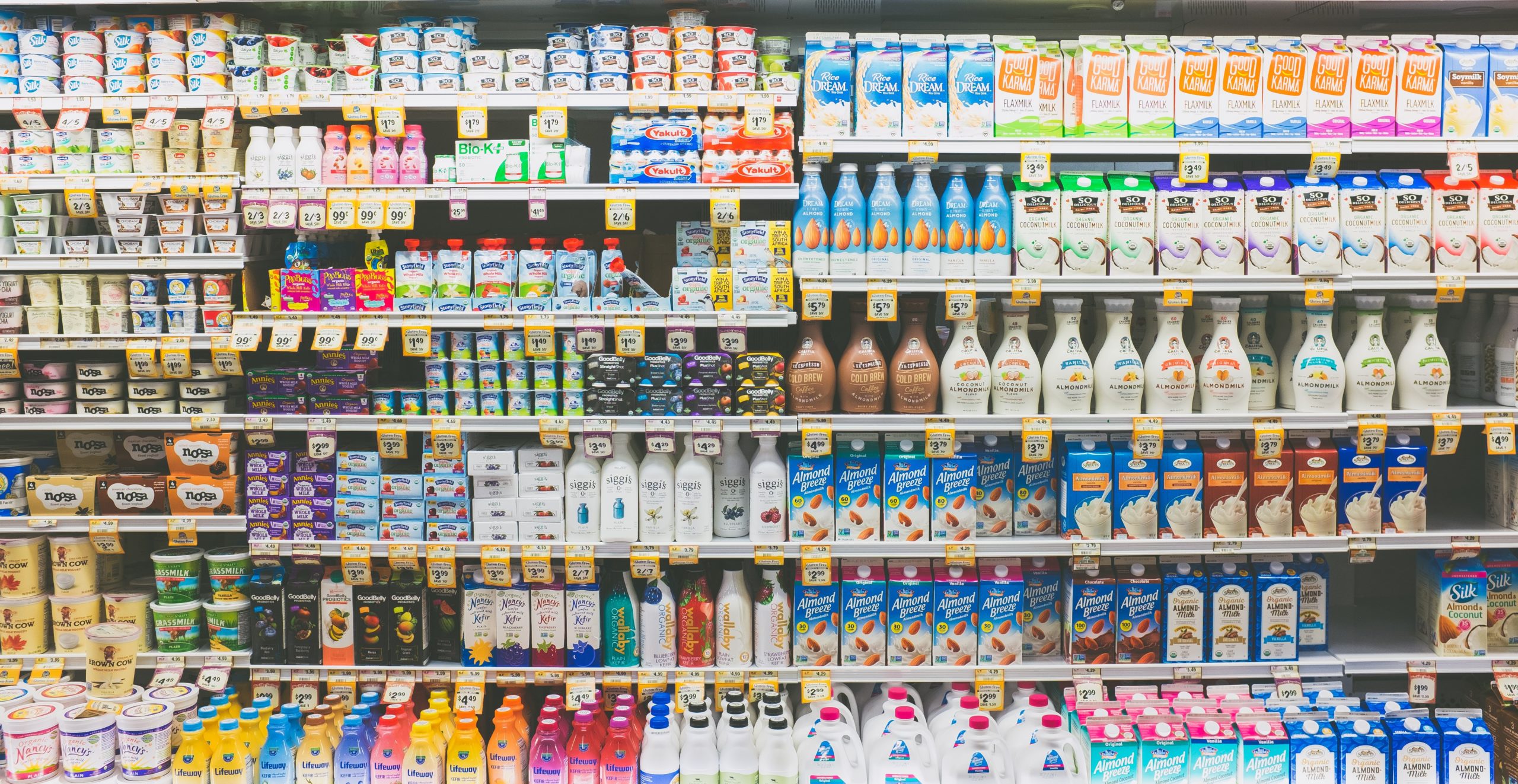 a cold beverage shelf in a supermarket showing gmo and non-gmo labels