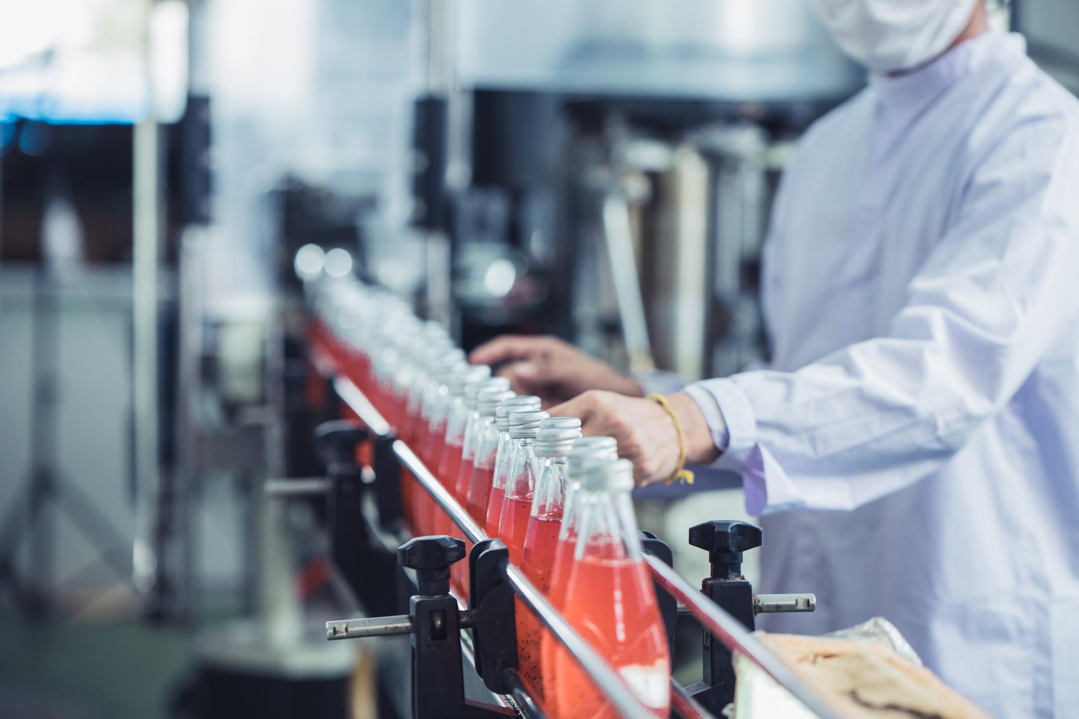 Drink factory - closeup beverage industry hygiene worker working check juice glass bottled in production line